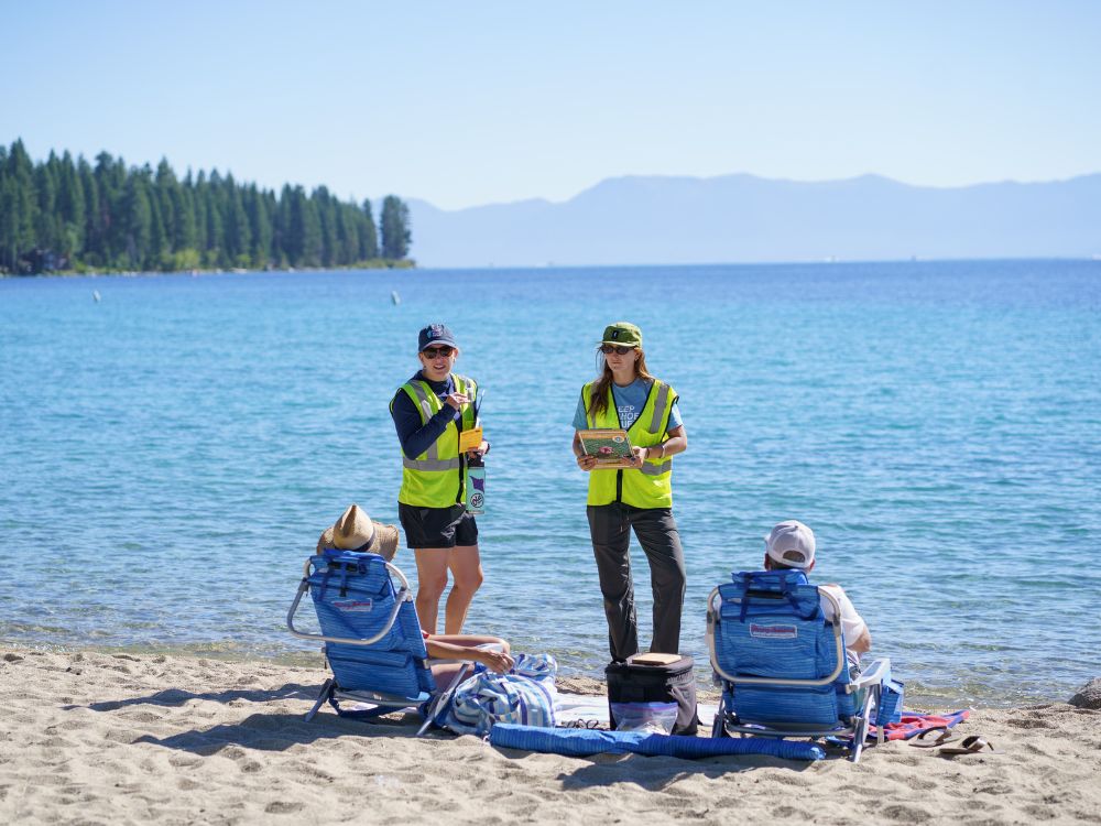 Keep Tahoe Blue Aquatic Invasive Species Defense Team members speaking with beachgoers about preventing the spread of aquatic invasive species at Lake Tahoe.