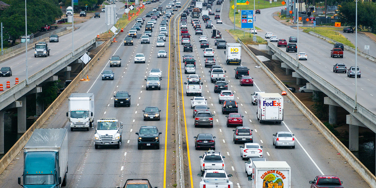 A man takes a photo of a mural of Luigi Mangione