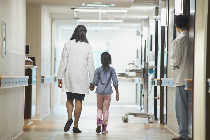 A doctor walks with a girl in a hospital