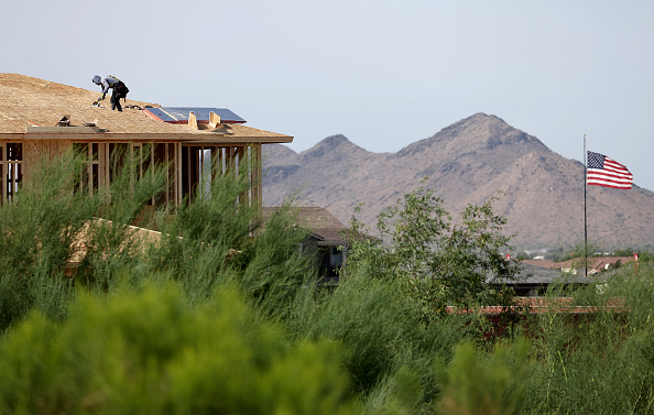 A person works on a rooftop during new home construction at a housing development in the Phoenix suburbs.