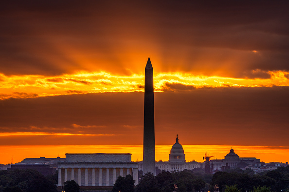 The rising sun behind the Lincoln Memorial, Washington Monument, and the U.S. Capitol building
