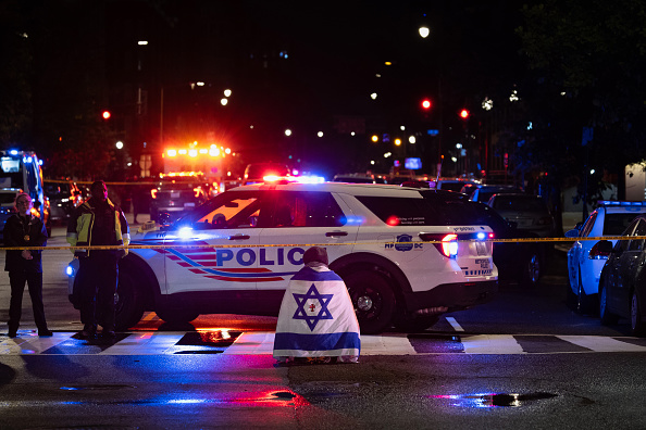 A bystander prays while wearing an Israel flag near the Capital Jewish Museum