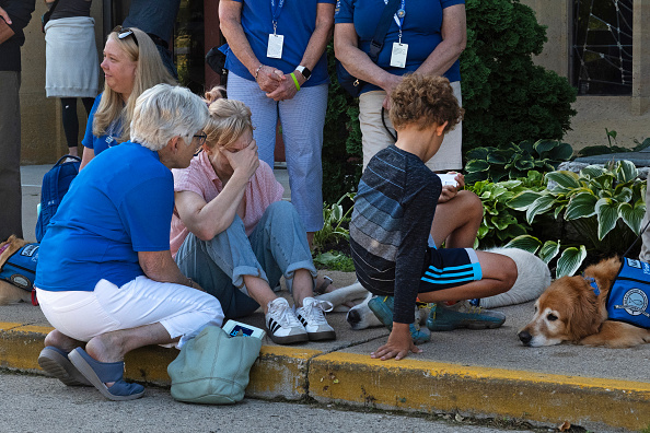 People interact with emotional support dogs provided by Lutheran Church Charities Comfort Dog Ministries near a memorial to shooting victims in front of Annunciation Catholic Church on August 28, 2025 in Minneapolis, Minnesota.
