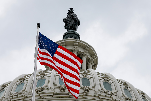 A United States flag waves in front of the United States Capitol building