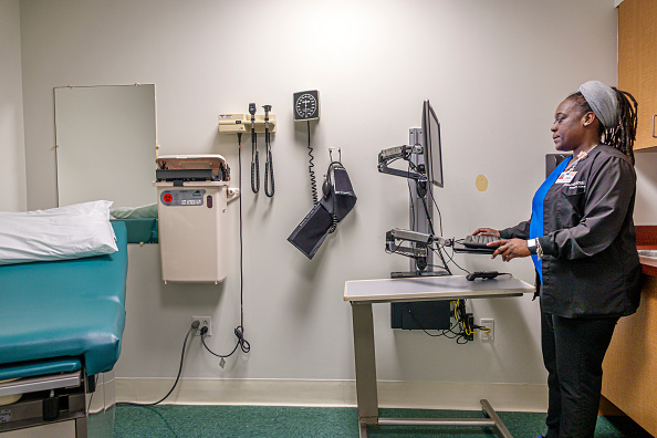 A nurse at a computer inside an exam room