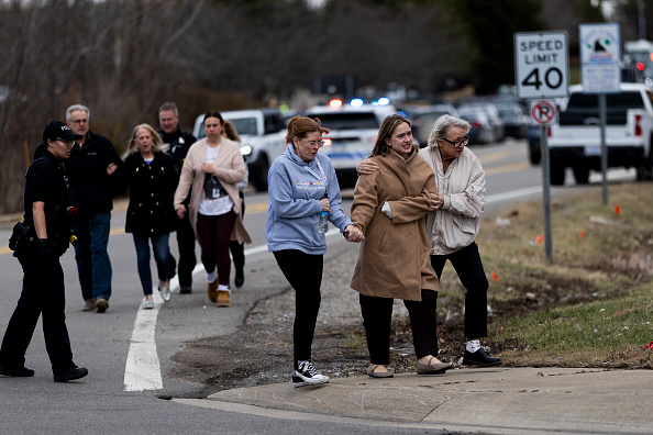 Employees make their ways back to their cars as law enforcement escorts them following an active shooter near Temple Israel