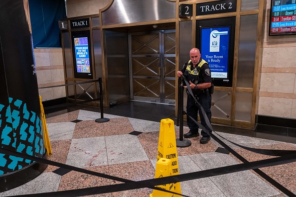 An Amtrak police officer moves barriers at the scene of a stabbing in Penn Station