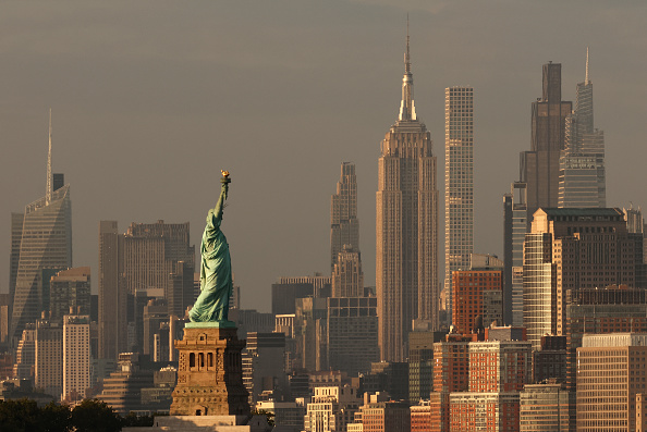 The sun sets on the Statue of Liberty, the Empire State Building and 432 Park Avenue in New York City