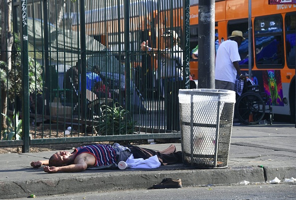 A man lays passed out beside a garbage can on the street in Los Angeles