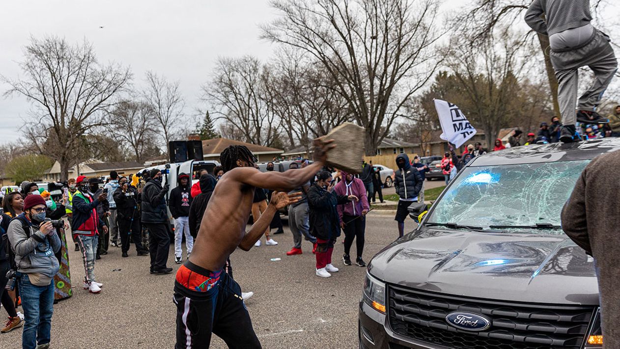 A man throws a rock at a police car in Minneapolis, Minnesota.